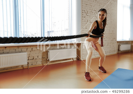 Woman with battle ropes exercise in the fitness gym. 49299286