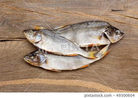 Three dried fishes on a wooden table. 49300604