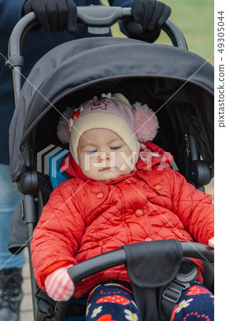 The little baby is sitting in the pram. 49305044