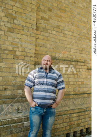 Fat man in the park looks into the frame, a Fat man in the park looks into the frame, a 49307771