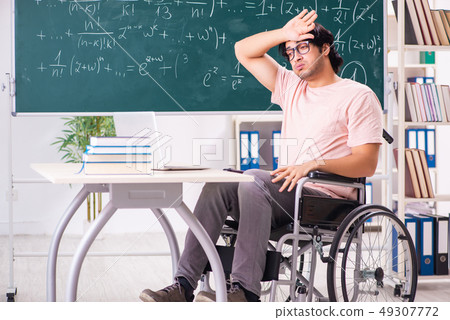 Young handsome man in wheelchair in front of chalkboard Young handsome man in wheelchair in front of chalkboard 49307772