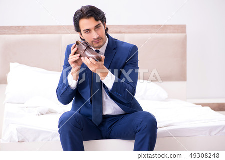 Young handsome businessman choosing shoes at home Young handsome businessman choosing shoes at home 49308248