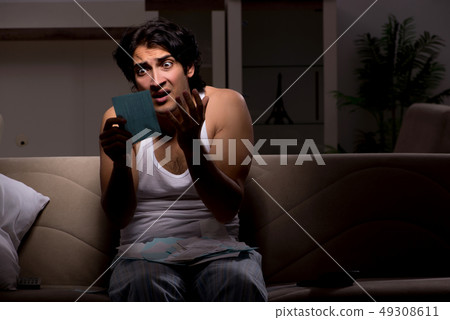Young man calculating expences night at home Young man calculating expences night at home 49308611