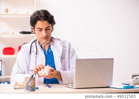 Young male doctor with human's skull  49312503