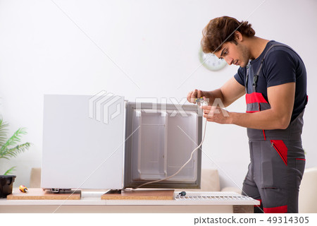 Young handsome contractor repairing fridge  49314305
