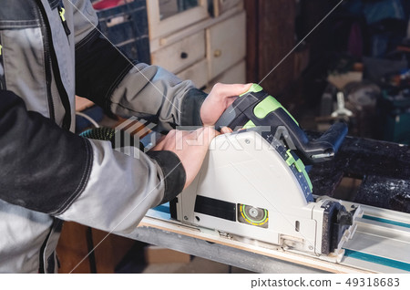 Close-up manual circular power saw in the hands of a worker in a home workshop. Starting a business 49318683