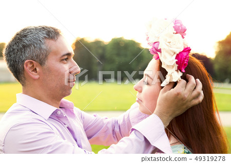 Man putting flowers wreath on his girlfriends head Man putting flowers wreath on his girlfriends head 49319278