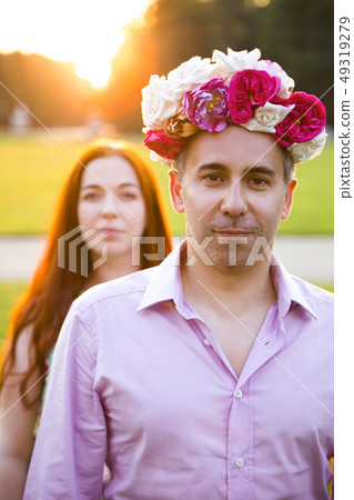 Couple fooling around with flowers wreath oudoors Couple fooling around with flowers wreath oudoors 49319279