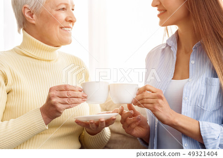 Happy mother and daughter toasting tea, enjoying breakfast 49321404