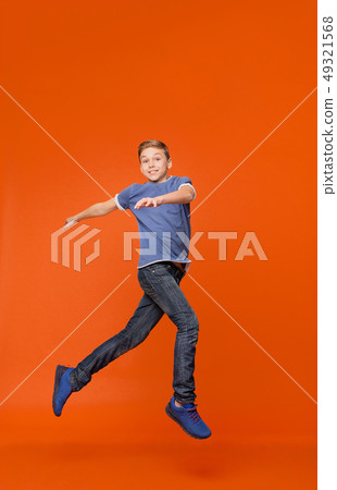 Cute boy dancing, jumping in air on orange backgrouns Cute boy dancing, jumping in air on orange backgrouns 49321568