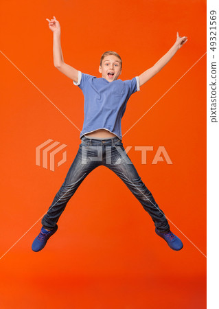 Happy boy jumping and raising his hands up Happy boy jumping and raising his hands up 49321569