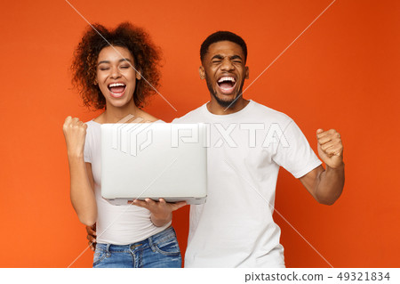 Excited black couple celebrating win with laptop 49321834