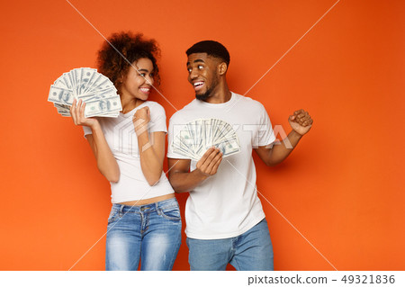 Cheerful african-american man and woman enjoying lots of money 49321836