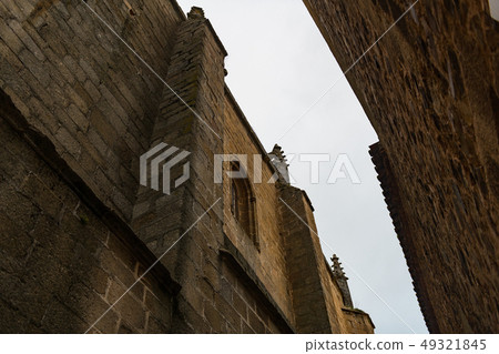 Narrow view of the sky between the high walls of the buildings of the old town of Caceres. 49321845