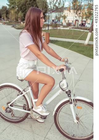 A girl on a bicycle, in summer in the city, a walk in the fresh air, an active sports lifestyle of A girl on a bicycle, in summer in the city, a walk in the fresh air, an active sports lifestyle of 49322765