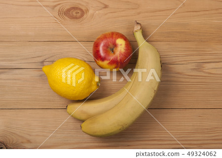Lemon apple and bananas on a wooden background. 49324062
