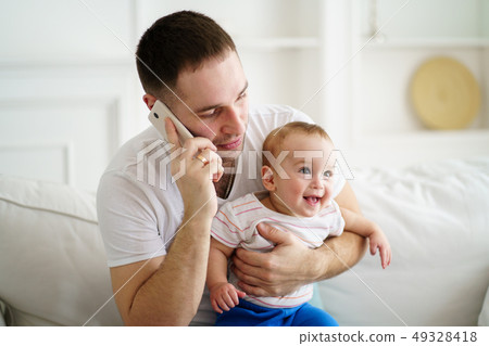 father working, talking on phone and babysitting father working, talking on phone and babysitting 49328418