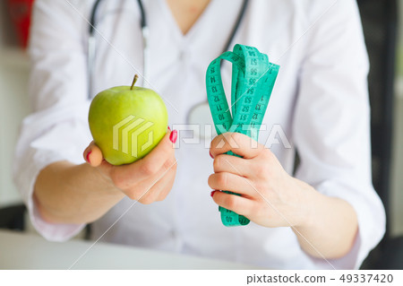 Diet. Female Nutritionist and Holding an Apple and a Measure Tape. New Start For Healthy Nutrition Diet. Female Nutritionist and Holding an Apple and a Measure Tape. New Start For Healthy Nutrition 49337420