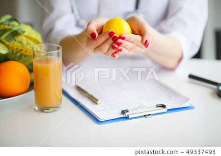 Conceptual Photo Of A Female Nutritionist With Fruits On The Desk Conceptual Photo Of A Female Nutritionist With Fruits On The Desk 49337493
