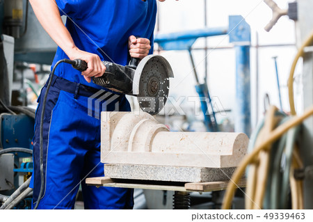 Female sculptor cutting stone with angle grinder 49339463