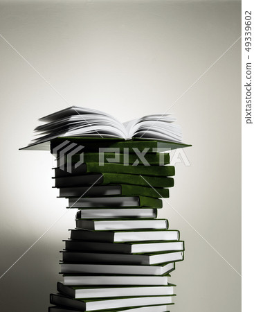 An open book on a stack of red books in the form of a spiral. 49339602