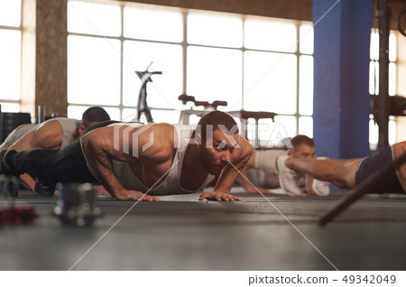 Small Group of Muscular Male Adults Warming Up Training Push Ups. 49342049