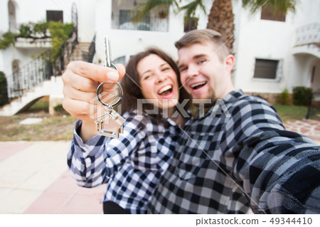 New Home, real estate and moving concept - Funny young couple showings keys from new house. New Home, real estate and moving concept - Funny young couple showings keys from new house. 49344410