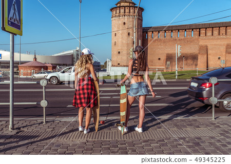 Two girlfriends girl, against background of road transition, stand with skateboards, longboard, view Two girlfriends girl, against background of road transition, stand with skateboards, longboard, view 49345225