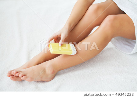 Waxing. Beautician Waxing Woman's Leg In Spa Salon 49345228