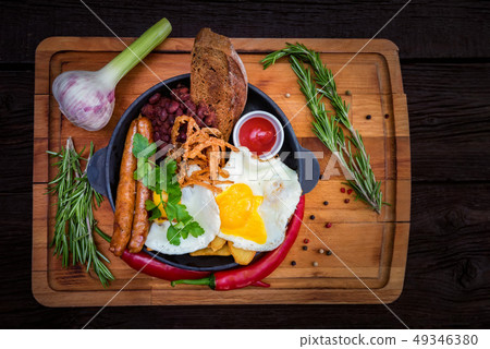 Nutricious meal with fried egg, sausages, beans, onion rings, chili pepper Nutricious meal with fried egg, sausages, beans, onion rings, chili pepper 49346380