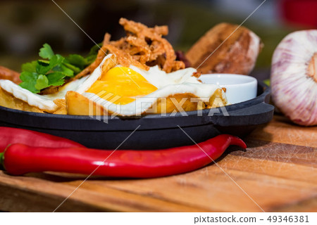 Nutricious meal with fried egg, sausages, beans, onion rings, chili pepper 49346381