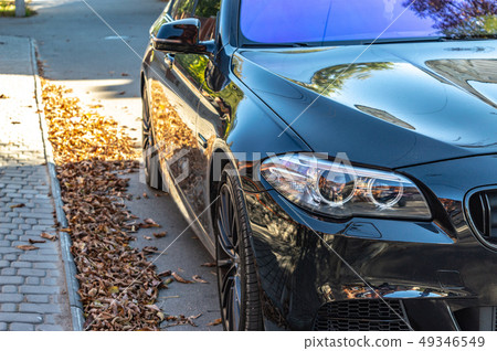 Dark sports car stands on the road in autumn sunny day close-up Dark sports car stands on the road in autumn sunny day close-up 49346549