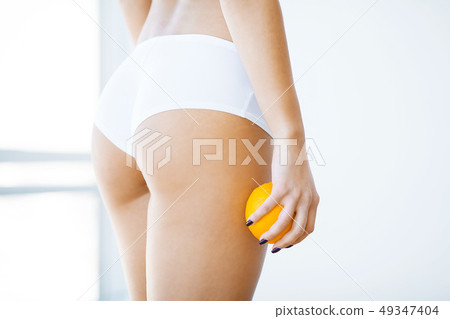 Diet and skin care. Beautiful Slim Woman Figure With an Orange Near Her Ass 49347404