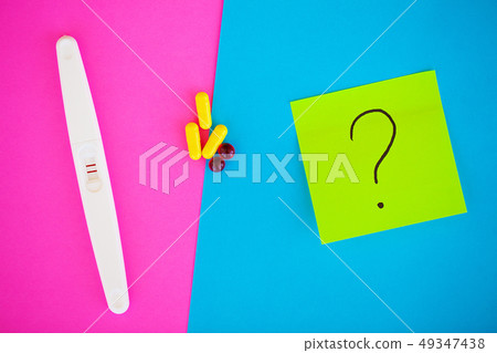 Pregnancy test. The result is positive with two strips and condom with contraceptive on colored 49347438