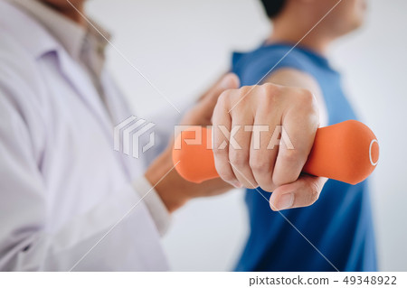 Doctor physiotherapist assisting a male patient Doctor physiotherapist assisting a male patient 49348922