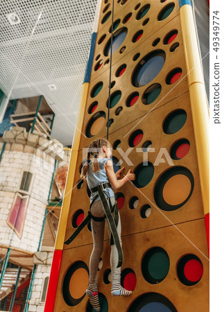 Girl climbing walls in game center, bottom view 49349774