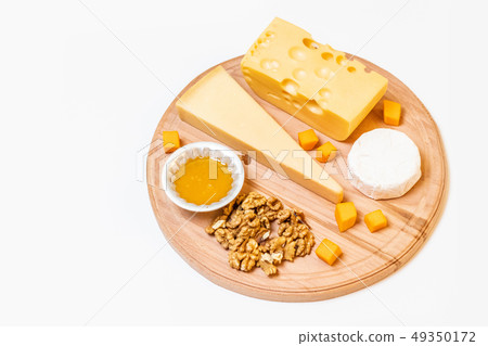Assorted cheeses on round wooden board plate Assorted cheeses on round wooden board plate 49350172