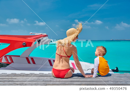 Toddler boy with mother sitting on wooden jetty 49350476
