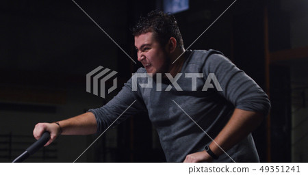Overweight young man exercising with a machine Overweight young man exercising with a machine 49351241