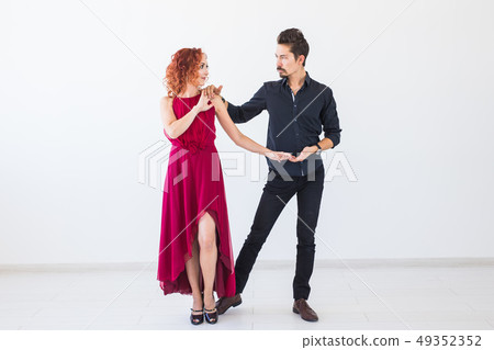 Social dance, bachata, kizomba, salsa, tango concept - Woman dressed in red dress and man in a black Social dance, bachata, kizomba, salsa, tango concept - Woman dressed in red dress and man in a black 49352352