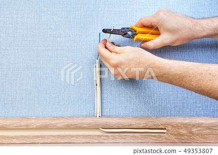 Stripping ends of wires with hand tool. 49353807