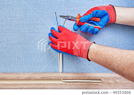Electrician cuts wires with hand tool. 49353808