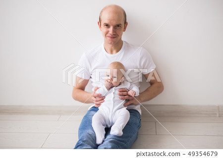 Infant, family and children concept - Bald father takes care of his little baby Infant, family and children concept - Bald father takes care of his little baby 49354679