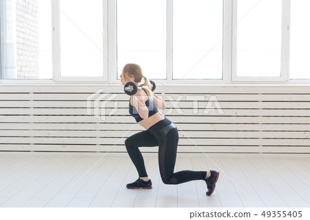 Fitness, healthy and sport concept - Woman with barbell flexing muscles and making lunge 49355405