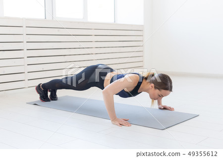 People, healthy and sport concept- Young sporty attractive woman doing push ups People, healthy and sport concept- Young sporty attractive woman doing push ups 49355612