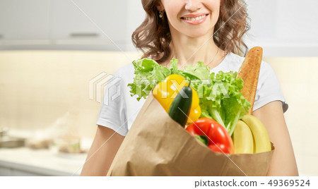 Woman keeping paper bag with food at kitchen Woman keeping paper bag with food at kitchen 49369524