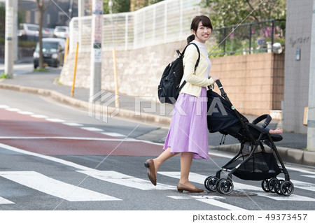 Mother pushing a stroller crossing a pedestrian crossing 49373457