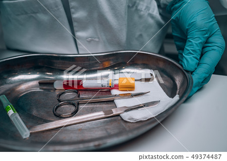 Nurse in rubber gloves holding a tray of surgical medical equipment Nurse in rubber gloves holding a tray of surgical medical equipment 49374487