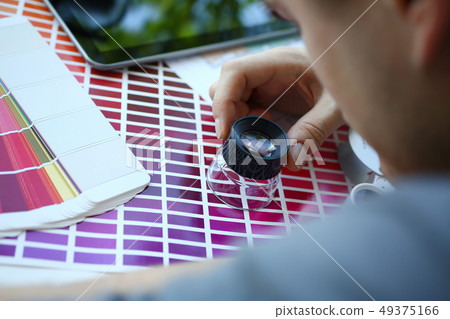 Male serviceman hold in hand magnifying glass making colour test Male serviceman hold in hand magnifying glass making colour test 49375166