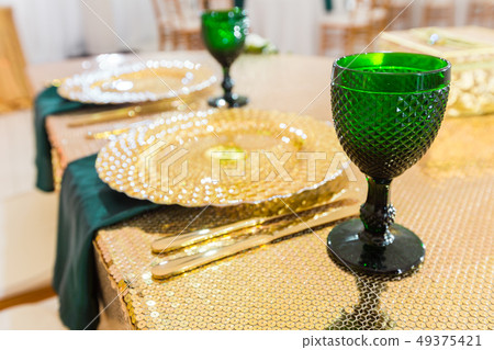 Golden dishes, green wine glasses and napkins. Catering concept. Interior of tent for wedding dinner 49375421